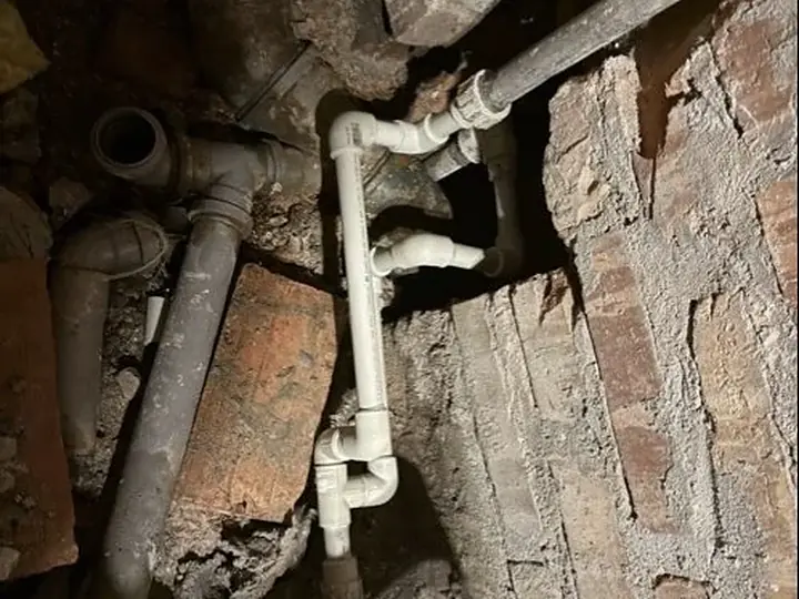 Stare rury żeliwne i PVC w rozkutej ścianie — DobryHydraulik Wrocław