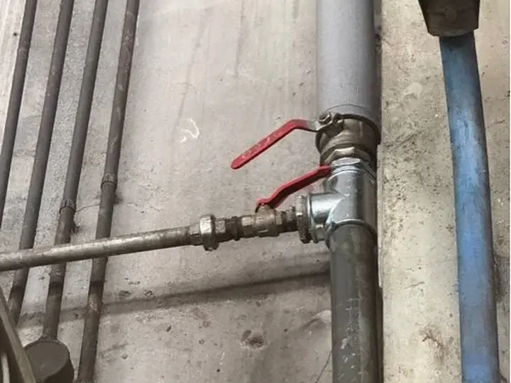 Główny zawór z czerwoną rączką na rurach — DobryHydraulik Wrocław